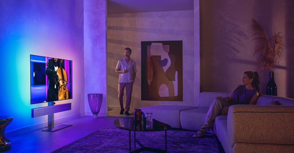 Mees ja naine stiilses elutoas vaatavad Philipsi Ambilight-telerit, millelt avaneb tšelloesinemine