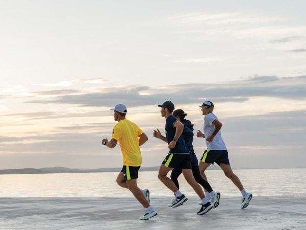Neli jooksjat jooksevad koos rannas.